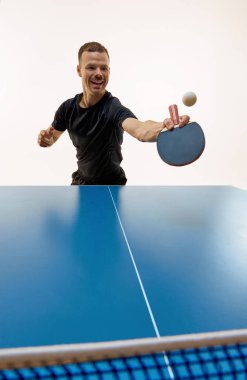 Oyuna odaklanmış, pinpon topu sporcusuna gözünü dikmiş, beyaz arka planda hareket eden tenis oyuncusu eğitimine odaklanmış. Profesyonel spor, dinamik ve enerji kavramı, şampiyonluk, turnuva. Ad.