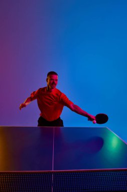 Atletik konsantre adam eğitiminin portresi topa vuruyor, neon ışıkta hareket halindeki saldırı tekniği arka planda eğilim gösteriyor. Dinamik jel portresi. Profesyonel spor, eğlence anlayışı. Ad