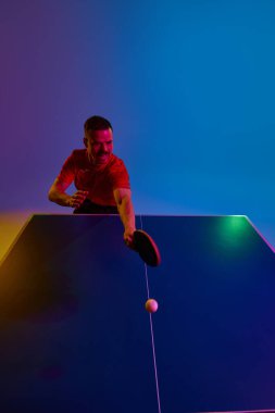 Maça odaklanmış, pinpon topu sporcusuna gözünü dikmiş, tenisçi eğitimini mor-mavi renge karşı sürdürüyor. Dinamik jel portresi. Profesyonel spor anlayışı, enerji. Ad