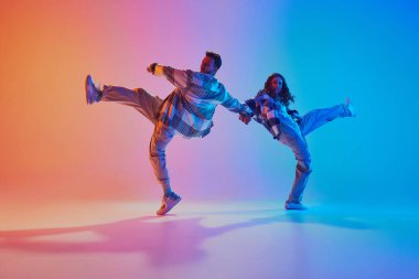Yetenekli ve yaratıcı serbest stil dansçıları gradyan stüdyo geçmişine karşı hareket ediyorlar. Senkronize hareketler. Moda ve tarz kavramı, enerji, dans savaşları. Dinamik jel portresi