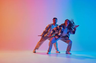 Neon ışıkta dans eden koordine dans çiftinin tam boy portresi. Sıvı hareketi. Hareket halindeki uyum, insanlar enerjiyi ifade eder. Müzik anlayışı, ritim, dans savaşları. Dinamik jel portresi