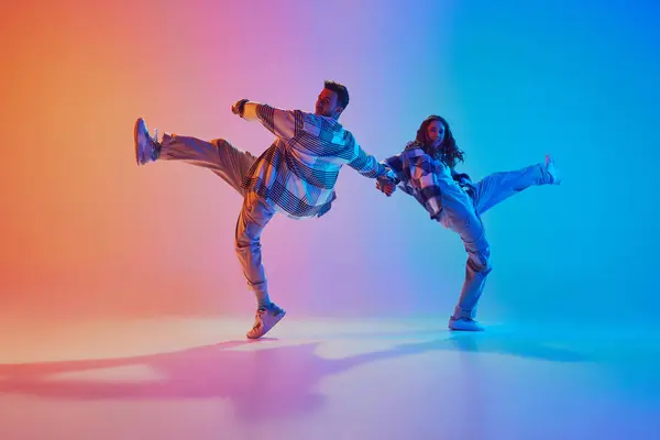 Talented and creative freestyle dancers performing in motion against gradient studio background. Synchronized movements. Concept of fashion and style, energy, dance battles. Dynamic gel portrait