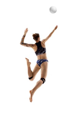 Genç bir kadının arkadan görünüşü, plaj voleybolcusu beyaz stüdyo arka planına karşı topa vuruyor. Spor oyunları, hareket, şampiyonluk, güç ve güç, dinamik ve enerji kavramı.