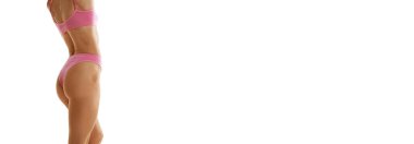 Pankart. Beyaz stüdyo arka planına karşı pembe iç çamaşırlarıyla poz veren zayıf esmer kadın portresi. Metin eklemek için negatif alan. Güzellik kavramı, tarz, moda, kozmetoloji, diyet. Ad