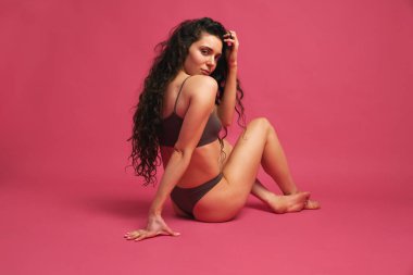 Hassas, ince esmer kadın portresi. Alnında iç çamaşırı olan, pembe stüdyo arka planında kameraya bakan kadın. Sağlık anlayışı, kadın sağlığı, sağlıklı yaşam tarzı, doğal güzellik, spa.