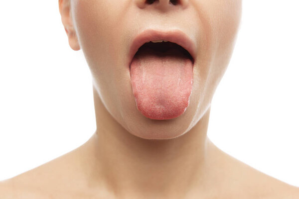 Close-up of female mouth with protruding tongue against white studio background. Concept of natural beauty, anti aging, cosmetology, oral hygiene, female health, dieting. Ad