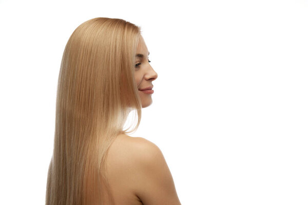 Портрет красивой женщины с длинными светлыми шелковистыми волосами, смотрящей в сторону на белом фоне студии. Уход за волосами. Понятие природной красоты, анти-старения, косметологии, женского здоровья. Объявление