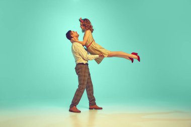Çekici bir çiftin dinamik portresi. Nane arkaplanına karşı retro tarzı kıyafetlerle dans ediyorlar. Sanat, hobi, müzik, enerji, mutluluk, ruh hali, eylem, klasik moda kavramı
