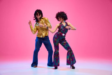Parlak kıyafetli harika dans eden çift gradyan pembe stüdyo arka planına karşı hareketli disko hareketleri sergiliyor. Amerikan kültürü kavramı, 1970 'ler, 1980' ler moda, müzik, çağların karşılaştırmaları..
