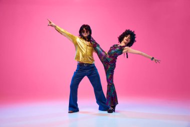 Retro dans stilleri. Çekici genç bir çift, erkek ve kadın gradyan pembe stüdyo geçmişine karşı disko yapıyorlar. Amerikan kültürü kavramı, 1970 'ler, 1980' ler moda, müzik, çağların karşılaştırmaları..