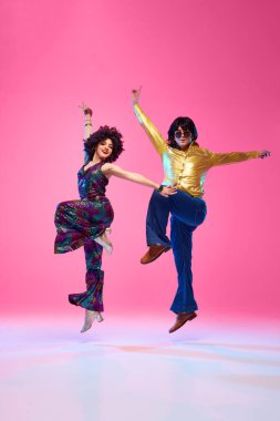 Yetenekli dansçılar, retro tarzı kıyafetler giymiş erkek ve kadın gradyan pembe stüdyo geçmişine karşı poz veriyorlar. Amerikan kültürü kavramı, 1970 'ler, 1980' ler moda, müzik, çağların karşılaştırmaları..