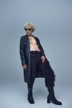 Modayı takip eden siyah elbiseli ve güneş gözlüklü adam gri stüdyo geçmişine karşı güçlü ve kendinden emin bir kişilik gösteriyor. Moda birleşimi, sanat fotoğrafçılığı, tarz, nonoşluk, eşsizlik, kendini ifade etme kavramı. Ad