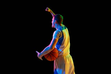Genç sporcunun arka plan portresi basketbol topunu tutuyor ve karışık neon ışıkta siyah stüdyonun arka planına bağırıyor. Profesyonel spor kavramı, enerji, güç, güç, maç, turnuva.