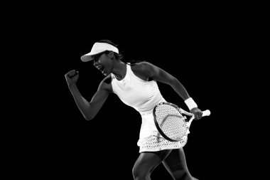 Mutlu ve keyifli bir kadın sevinçten bağırıyor çünkü gol atıp siyah stüdyonun arka planına karşı kazanıyorlar. Monokrom filtresi. Kadınların spor anlayışı, aktif yaşam tarzları, turnuvalar, hareketler.