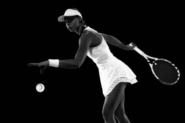 Formda bir kadın, tenisçi siyah stüdyo geçmişine karşı mükemmel servis yapmak için topu atar. Monokrom filtresi. Kadınların spor anlayışı, aktif yaşam tarzları, turnuvalar ve etkinlikler, enerji, hareket.