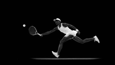Tenis oyuncusunun hareketli bir fotoğrafı. Siyah stüdyo arka planına karşı hareket halinde. Monokrom filtresi. Spor anlayışı, aktif yaşam tarzları, turnuvalar ve etkinlikler, enerji, hareket.