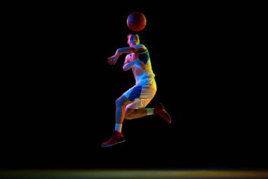 Genç sporcunun aksiyon fotoğrafı, basketbolcu karışık neon ışıkta siyah stüdyonun arka planına pas veriyor. Profesyonel spor kavramı, enerji, güç ve güç, maç, şampiyonluk.
