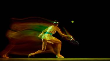 Genç bir kadının hareketli bulanık bir şekilde siyahların arka planına vurmaya hazırlandığı dinamik bir fotoğraf. Hızlı hareket spor anlayışı, aktif yaşam tarzları, turnuvalar, rekabet, enerji. Ad