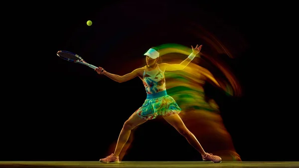 Athletic woman on tennis court with swirl of colors highlighting motion against black studio background. Speed and motion. Concept of sport, active lifestyles, tournaments and events, energy, movement