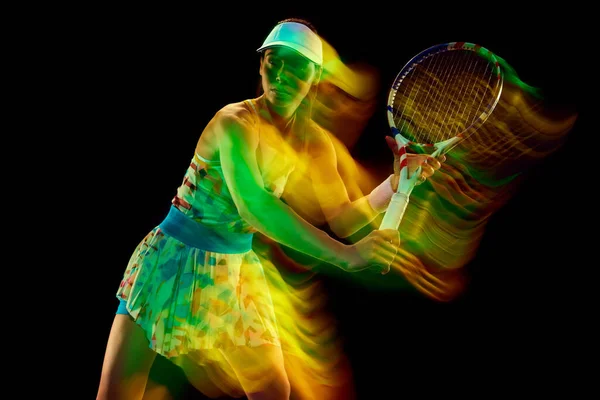Sportive woman, tennis athlete playing backhand stroke against black studio background Motion blur effect. Concept of sport, active lifestyles, tournaments and events, energy, movement.