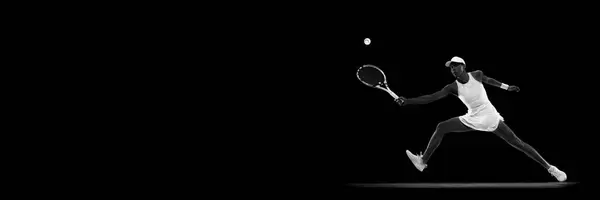 Banner. Tennis player jumping to hit overhead shot in motion against black studio background. Monochrome filter. Concept of sport, active lifestyles, tournaments and events, energy, movement.