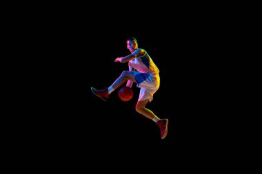 Basketbolcuların aksiyon sahnesi karışık neon ışıkta siyah stüdyo arkaplanına karşı top sürüyor. Profesyonel spor, enerji, güç ve güç kavramı, maç, şampiyonluk, turnuva.