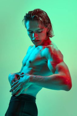 Çekici genç adamın yan görünüş portresi. Nane arkaplanına karşı kırmızı-mavi ışık saçan kaslar. Doğal güzellik insanları, fitness, erkek sağlığı ve refahı, erkeklik kavramı.