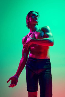 Atletik erkek model, semer ve morumsu ışığın altında gradyan stüdyo arka planına karşı poz veriyor. Güven ve güzellik. Doğal güzellik insanları, fitness, erkek sağlığı ve refahı, erkeklik kavramı.