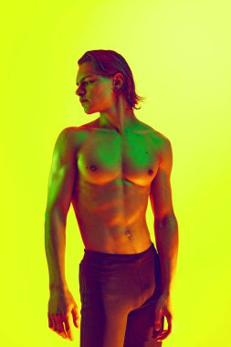 Atletik bir adamın portresi, rengarenk neon ışıkta farklı yönlere bakan sarı arka planda kayboluyor. Doğal güzellik insanları, fitness, erkek sağlığı ve refahı, erkeklik kavramı.