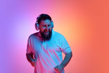 Aşırı neşeli sakallı bir adam kulaklıkla müzik dinliyor ve parlak bir ışıkla dans ediyor. Rahatlama, insani duygular, kendini ifade etme, güzellik ve moda kavramı. Ad