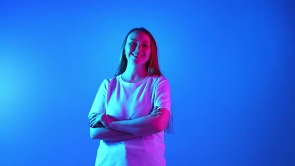 Młoda Kobieta Białym Shircie Patrząca Kamerę Uśmiechniętymi Skrzyżowanymi Dłońmi Neonowym — Wideo stockowe