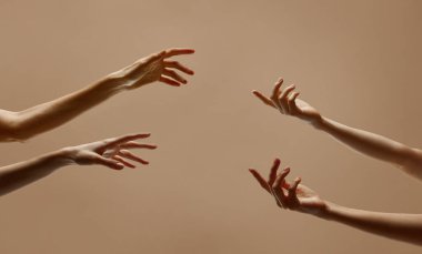 Bej renkli stüdyo arka planında birbirine uzanan dört insan eli fotoğrafı. Okşamak. Hisset. İnsan dokunuşu, güzellik ve bakım kavramı, spa prosedürleri, sağlık.