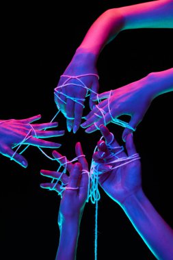 Eller beyaz iplikle birleştiğinde yıldız şekli oluşur ve siyah stüdyo arka planına karşı çok renkli neon ışıkta küresel iletişimi sembolize eder. İnsan dokunuşu, güzellik ve sanat kavramı.