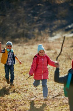 Pembe ceketli neşeli çocuk, güneş ışığıyla dolu sahada oyun arkadaşlarını canlandırıyor. Çocuk gelişimi, okul, çocukluk, moda ve tarz için açık hava aktiviteleri kavramı. Ad