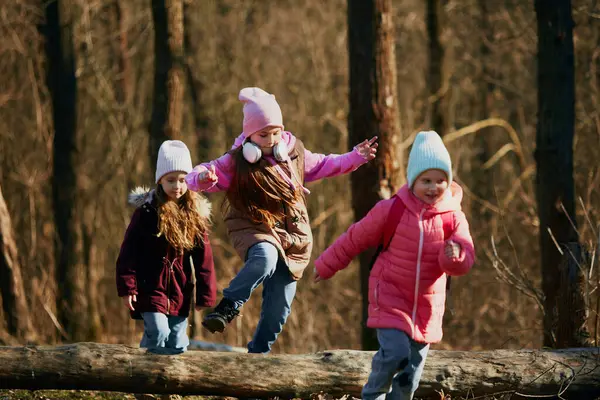 Pre-teens in winter outfit running, jumping energetically on dirt track outdoors. Environment lesson. Concept of outdoor activities for childrens development, school, childhood, fashion and style. Ad