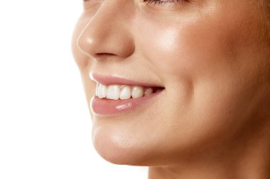 Dişleriyle beyaz stüdyo geçmişine gülümseyen genç bir kadının kesilmiş fotoğrafı. İyi korunmuş derisi ve sağlıklı gülüşü olan bir kadın model. Doğal güzellik insanları, enjeksiyonlar, sağlık, kozmetoloji kavramı
