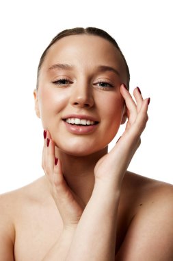 Saf ten rengine sahip zarif genç bayan beyaz stüdyo geçmişine karşı her gün doğal makyaj yapıyor. Kişisel bakım. Doğal güzellik insanları kavramı, iğneler, sağlık, spa prosedürleri, kozmetoloji.