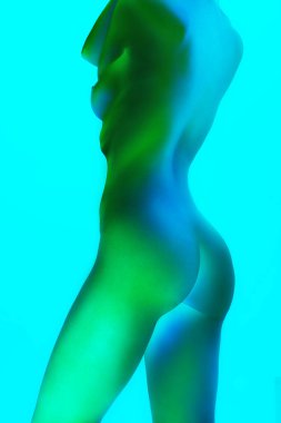 Genç, zayıf bir kadın, kıvrımları mükemmel. Neon ışıklarıyla, arka plandaki değişimlere karşı. Sanat ve kadınlık kavramı, kadın sağlığı, vücut bakımı, kendini ifade etme ve kendini sevme.