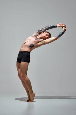 Kaslı, atletik vücutlu, iç çamaşırlarıyla poz veren çekici bir adam gri stüdyo geçmişine karşı kollarını kaldırıyor. Uzayı kopyala Doğal güzellik, moda ve tarz kavramı, erkek sağlığı ve vücut bakımı. Ad