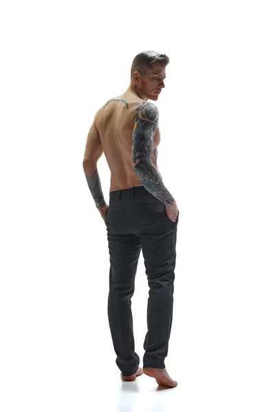 年轻纹身男子背对着白工作室背景摆姿势的后视镜画像 复制空间 自然美 时尚与时尚 男性健康与身体护理的概念 免版税图库图片
