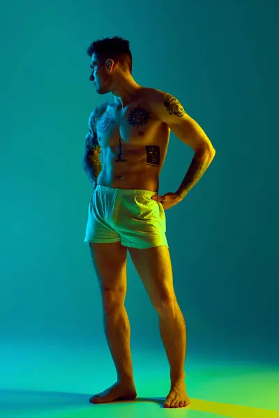 Tätowiert Posiert Ein Junger Mann Unterwäsche Auf Hüften Neonlicht Vor lizenzfreie Stockbilder