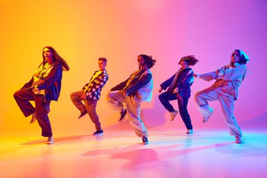 Tramvay tarzı giyinmiş genç dansçıların dinamik portresi neon ışıkta dans ederek gradyan stüdyo arka planına karşı. Hobi, spor, moda, aksiyon, gençlik kültürü, müzik konsepti.