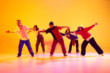 Yetenekli genç dansçılar, renkli stüdyo arka planlarına karşı neon ışıkta sokak dansı yapıyorlar. Hobi, spor, moda, aksiyon, gençlik kültürü, müzik ve dans kavramı.