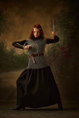 Kızıl saçlı prenses elinde çatal ve kapak taşıyan bir poz verdi. Kalkan ve kılıç gibi. Dönem, tarih ve modern zaman, güzellik ve moda karşılaştırmaları kavramı.
