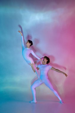 Performans ortasında bale ikilisi, erkek dansçı kadın dansçıyı hafif hareketlerle renkli arka plana karşı kaldırıyor. Güzellik ve zarafet kavramı, dans zarafeti, ilham, yaratıcılık.