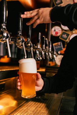 Bardaki fıçı bira fıçısından şişmanlatılan bira bardağının yakın çekimi. Soğuk, ferahlatıcı hafif bira cama işliyor. Alkol içecekleri, gece hayatı, parti, festivaller, Ekim Festivali. Ad