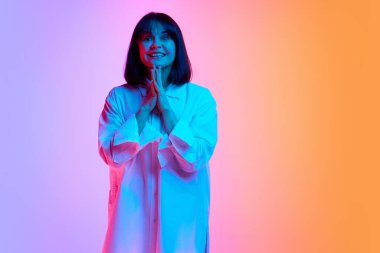 Kısa saçlı, iri yarı, neşeli suratlı bir kadın. Stüdyonun arka planına karşı neon ışıkta kameraya bakıyor. İnsan duyguları kavramı, moda, güzellik, tarz.