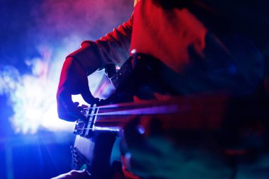 Profesyonel, yetenekli gitarist tarafından çalınan elektro gitar mavi neon ışıklar altında sahnede görünür dumanla birlikte. Rock müzik, hobi ve iş kavramı, enerji, müzik festivali, konser. Ad