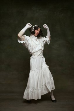 Orta çağ insanı gibi giyinmiş, orta çağ insanı gibi giyinmiş, kulaklıkla dans edip, klasik arka planda şarkı söyleyen genç annenin tam boy portresi. Kendini ifade etme kavramı, dönemin karşılaştırmaları, özgürlük. Ad