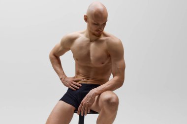Gri stüdyo geçmişine karşı iç çamaşırlarıyla poz veren genç bir atletik. Kas yapısı olan bir model. Erkek sağlığı, kişisel bakım, moda ve güzellik kavramı, sağlıklı yaşam tarzı. Ad
